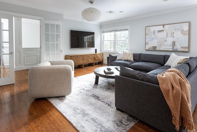 living area with crown molding, visible vents, and wood finished floors