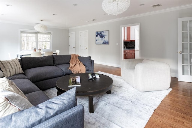 living area featuring visible vents, ornamental molding, and wood finished floors