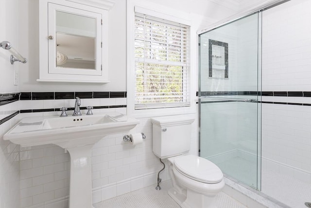 bathroom with toilet, tile patterned flooring, a shower stall, and tile walls