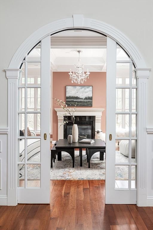 doorway with ornamental molding, arched walkways, wood-type flooring, and french doors