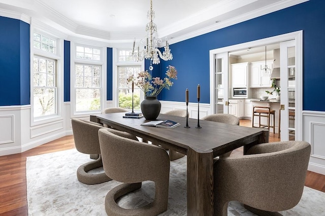 dining space with a wainscoted wall, a chandelier, and light wood-style floors