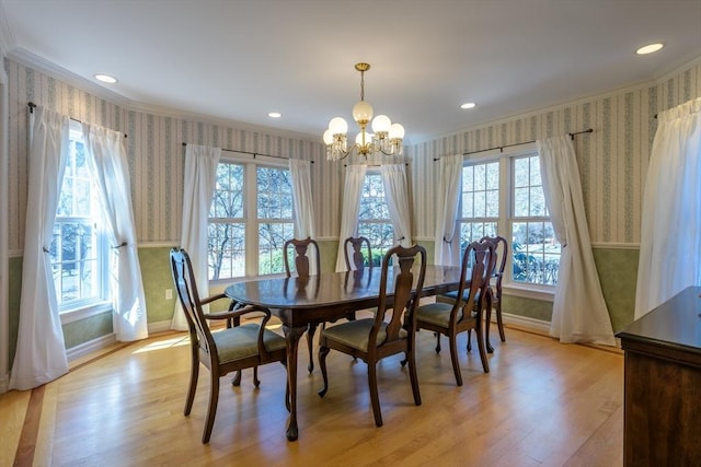 dining area with a notable chandelier, wallpapered walls, light wood-style floors, and ornamental molding