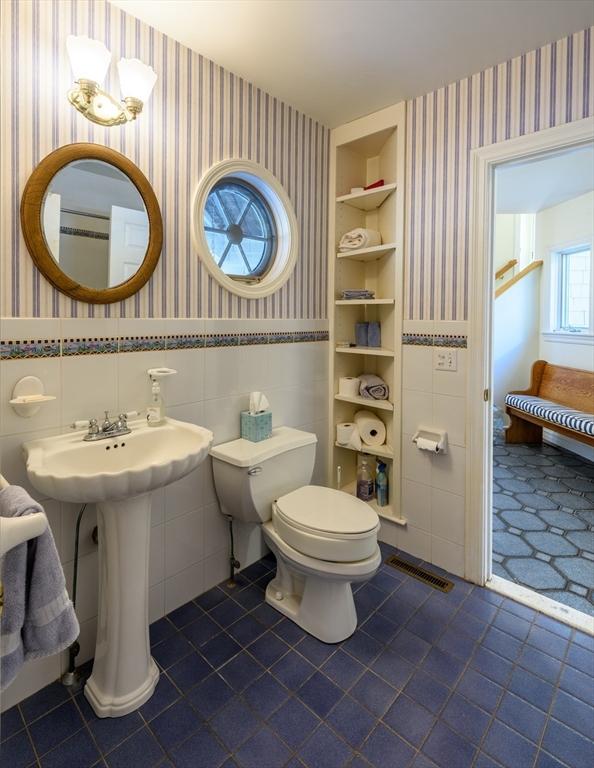 bathroom featuring built in shelves, toilet, and wallpapered walls