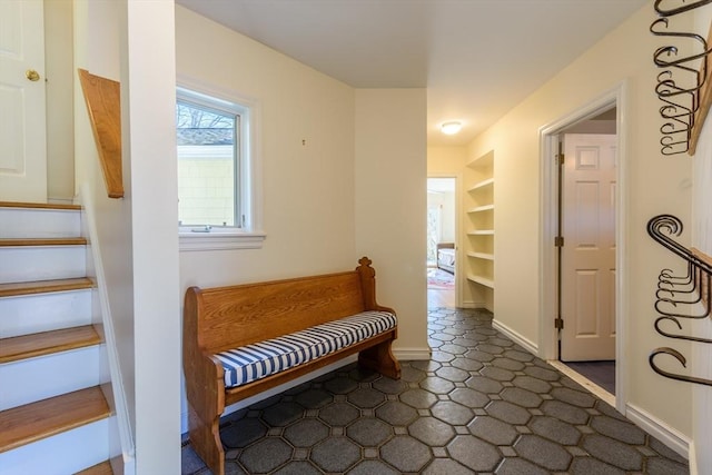 hallway featuring built in features, stairway, and baseboards