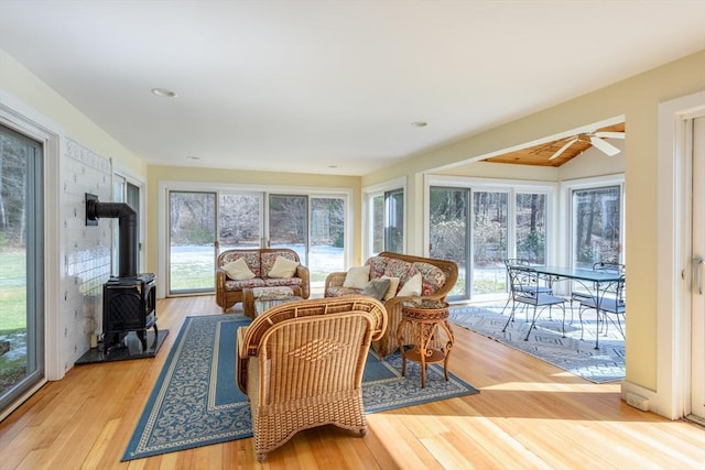 sunroom / solarium featuring a wealth of natural light, a wood stove, and a ceiling fan