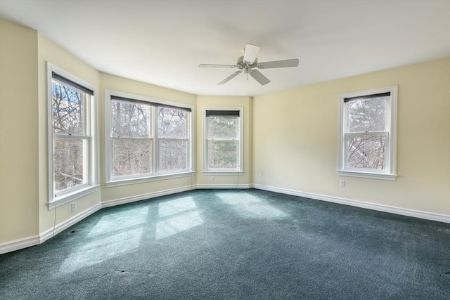 unfurnished room with baseboards, dark carpet, and ceiling fan