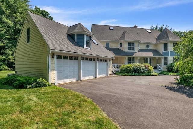 view of front facade with driveway, an attached garage, a porch, and a front lawn