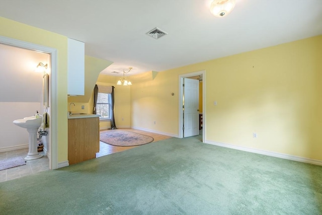 unfurnished living room featuring a sink, visible vents, light colored carpet, and an inviting chandelier