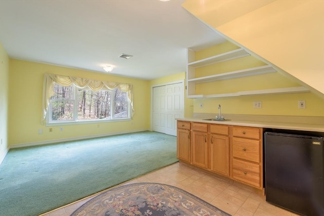 bar featuring visible vents, light carpet, a sink, fridge, and indoor wet bar