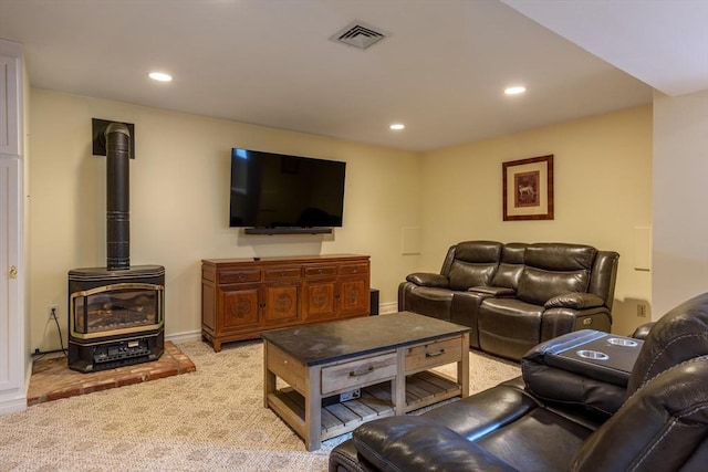 living area with recessed lighting, visible vents, light colored carpet, and a wood stove