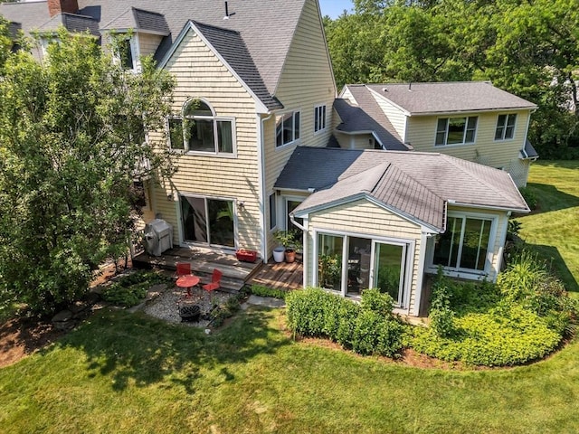 back of house featuring a lawn and a shingled roof