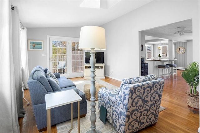 living room featuring baseboards, a ceiling fan, wood finished floors, and lofted ceiling