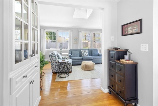 living room with light wood-style floors, baseboards, and a skylight
