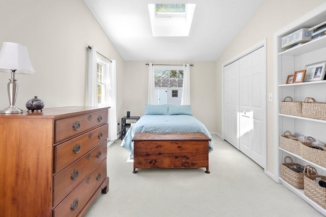 bedroom featuring light carpet, vaulted ceiling with skylight, and a closet