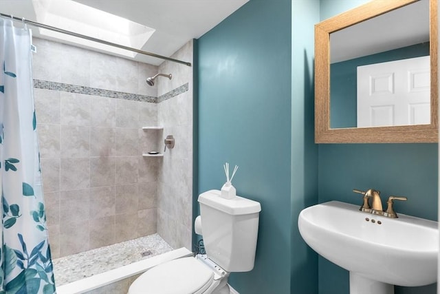 full bathroom featuring a sink, a skylight, toilet, and tiled shower