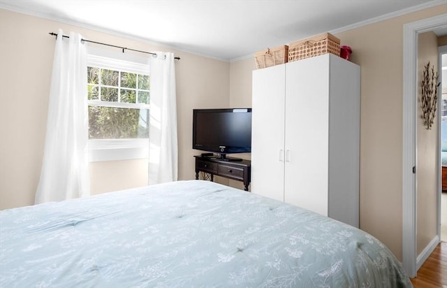 bedroom featuring ornamental molding and wood finished floors