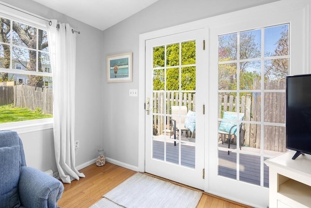 doorway featuring baseboards, wood finished floors, and lofted ceiling