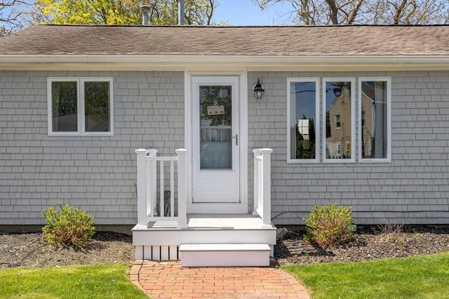 entrance to property featuring roof with shingles