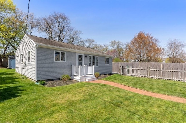 rear view of property featuring a lawn and fence