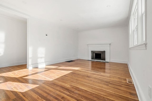 unfurnished living room featuring wood-type flooring, crown molding, and a fireplace