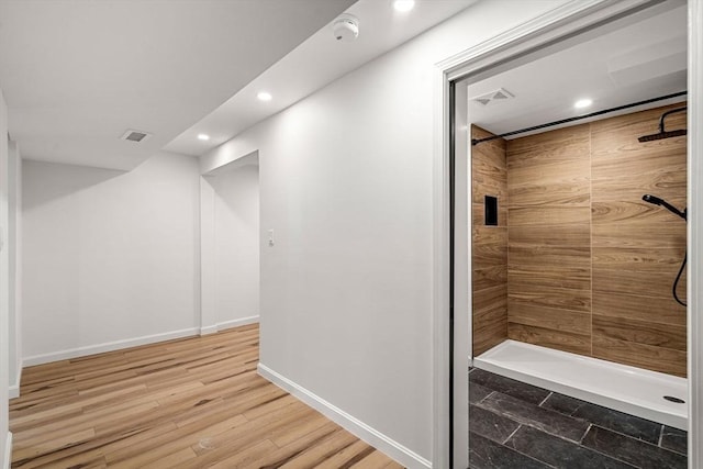 bathroom with tiled shower and wood-type flooring