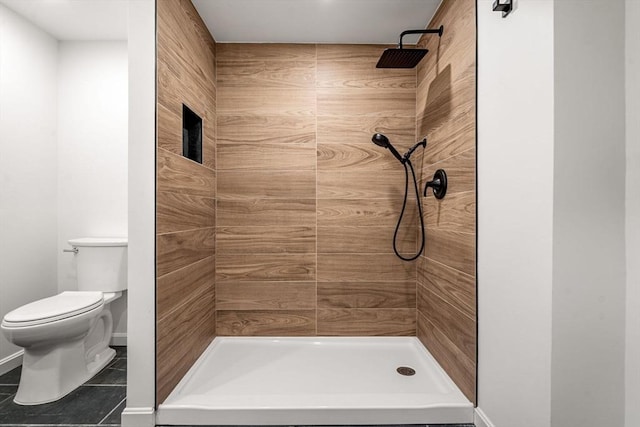 bathroom featuring tile patterned flooring, toilet, and tiled shower