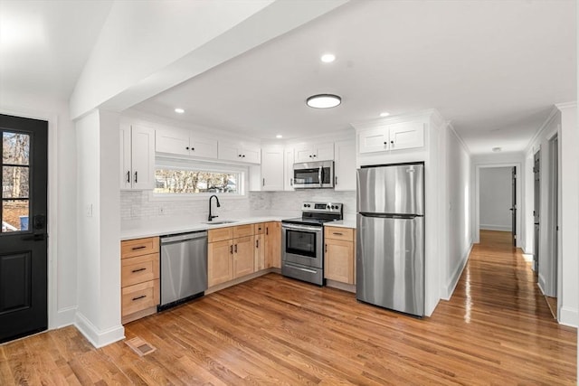 kitchen with sink, backsplash, stainless steel appliances, white cabinets, and light brown cabinetry