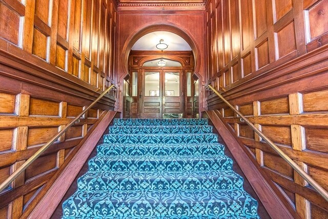 271 Dartmouth St Unit 5C, Boston, MA 02116 - staircase with wood walls, carpet floors, and arched walkways