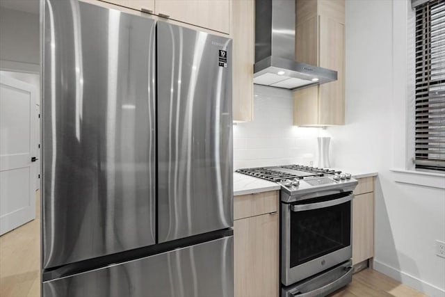 kitchen with stainless steel appliances, wall chimney range hood, light hardwood / wood-style floors, decorative backsplash, and light brown cabinetry