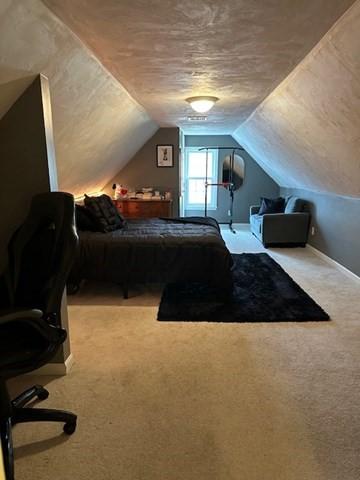 bedroom with lofted ceiling, carpet floors, and a textured ceiling