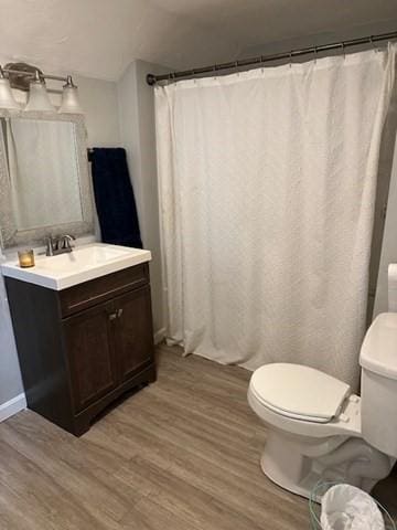 bathroom with wood-type flooring, vanity, toilet, and a shower with curtain