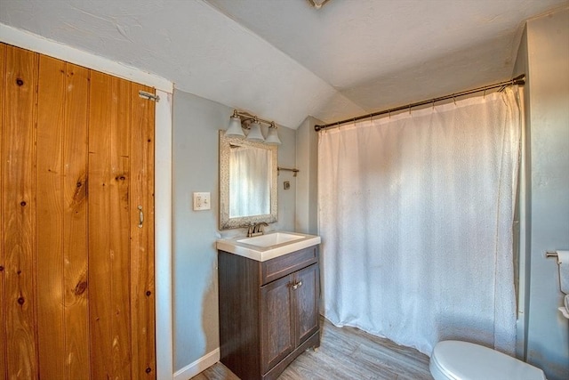 bathroom featuring hardwood / wood-style floors, vanity, lofted ceiling, toilet, and curtained shower