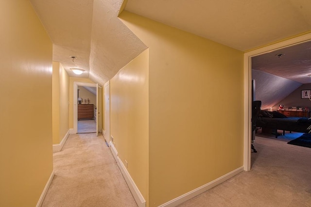 hallway featuring light carpet and vaulted ceiling