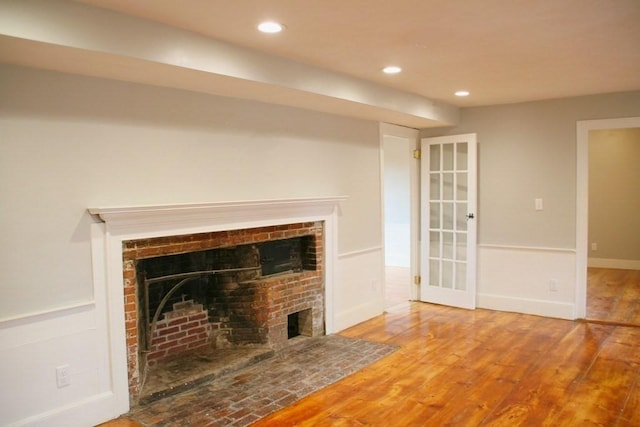 unfurnished living room featuring wood-type flooring and a brick fireplace