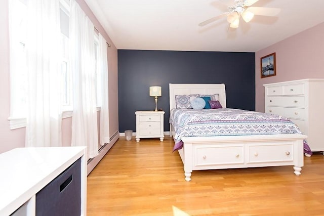 238 Rock St Unit C8, Norwood, MA 02062 - bedroom with a baseboard heating unit, light wood-style floors, an accent wall, and a ceiling fan
