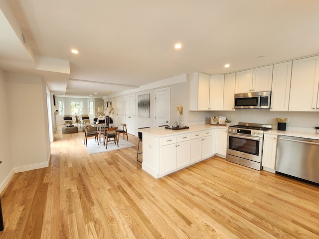 kitchen with white cabinetry, light wood-type flooring, kitchen peninsula, and appliances with stainless steel finishes