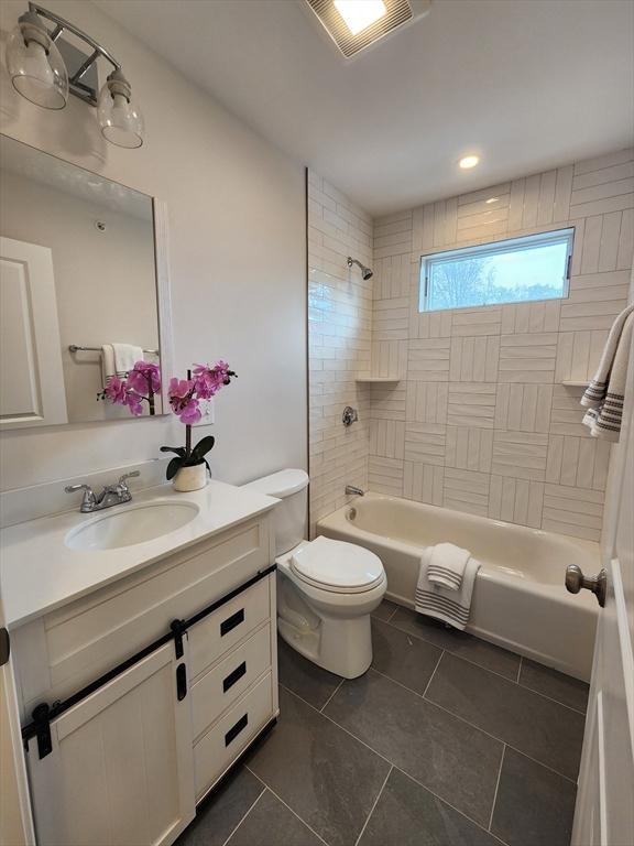 full bathroom with tile patterned flooring, tiled shower / bath combo, toilet, and vanity