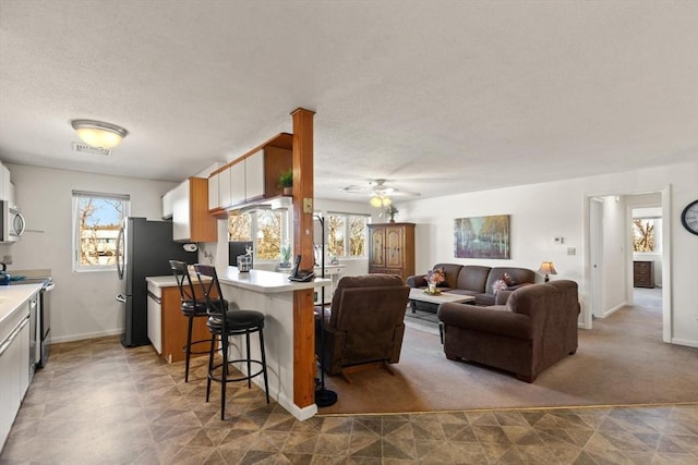 kitchen with a healthy amount of sunlight, stainless steel appliances, a kitchen breakfast bar, and white cabinets