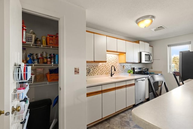 kitchen featuring sink, decorative backsplash, white cabinets, and appliances with stainless steel finishes