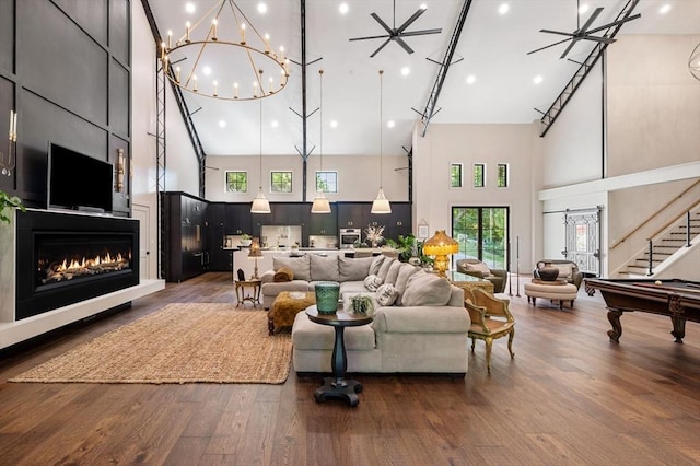 living room featuring a warm lit fireplace, stairs, a high ceiling, and dark wood-style flooring