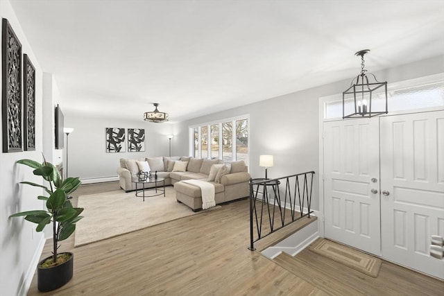 living room with a baseboard heating unit, baseboards, an inviting chandelier, and wood finished floors