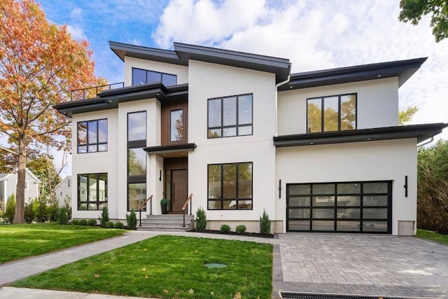 modern home featuring a front yard, decorative driveway, an attached garage, and stucco siding