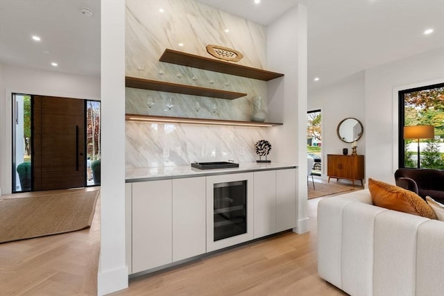 bar featuring tasteful backsplash, recessed lighting, light wood-style floors, and a bar