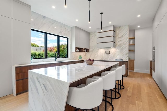 kitchen featuring tasteful backsplash, modern cabinets, a sink, and light wood-style floors