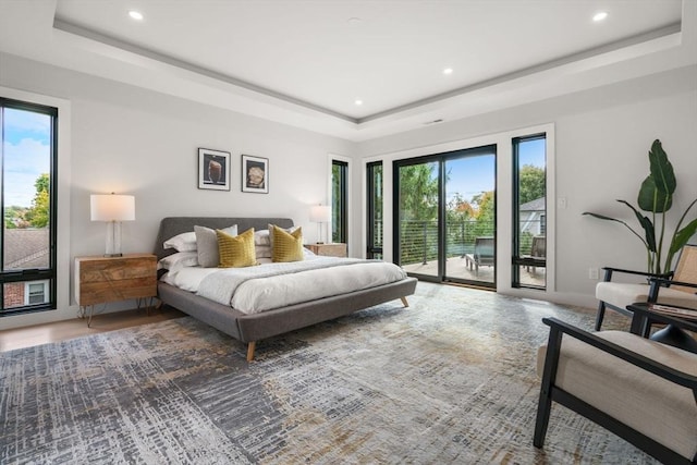 bedroom featuring access to exterior, multiple windows, a tray ceiling, and recessed lighting