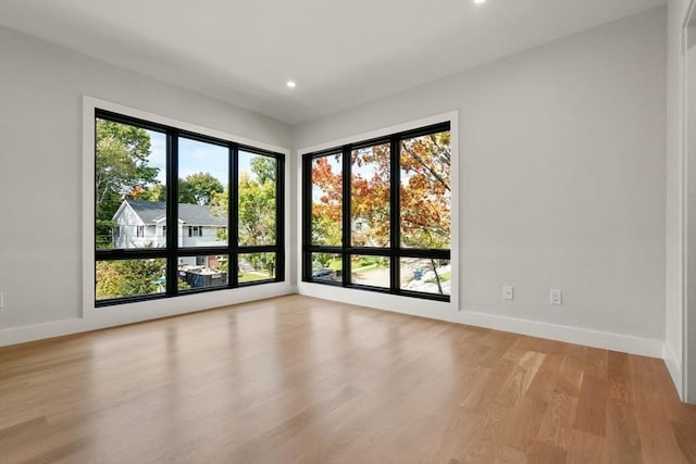 empty room featuring light wood-type flooring, baseboards, and recessed lighting