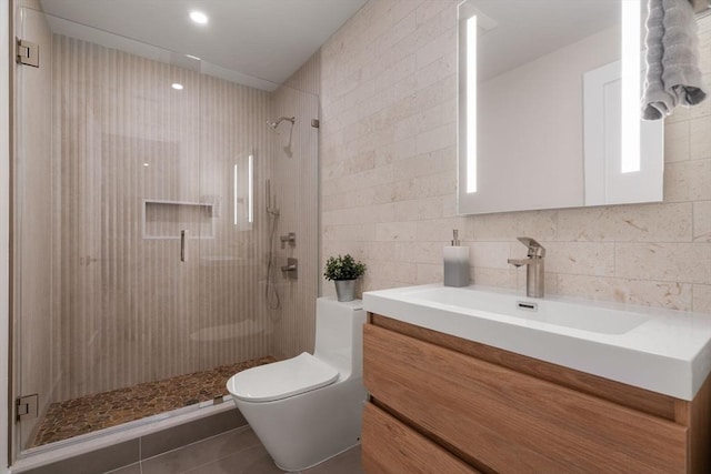 full bath with toilet, vanity, a shower stall, and tile walls