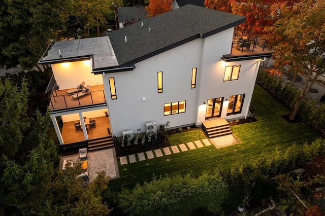 rear view of property with a lawn, a chimney, a balcony, and stucco siding