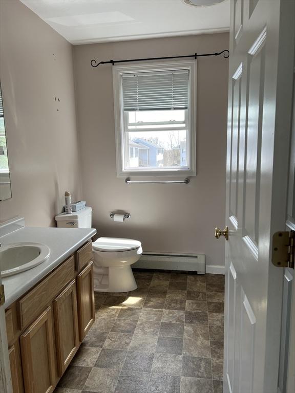 bathroom featuring a baseboard radiator, plenty of natural light, toilet, and vanity
