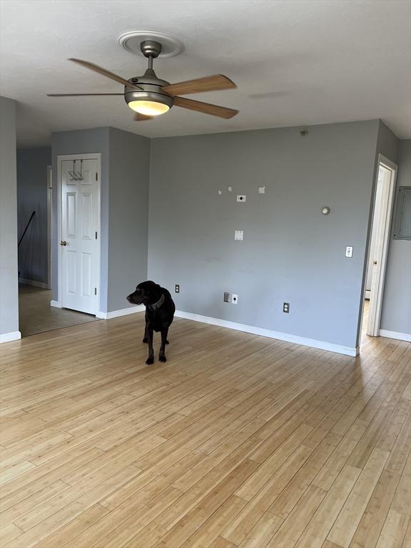 empty room featuring a ceiling fan, baseboards, and light wood-style flooring